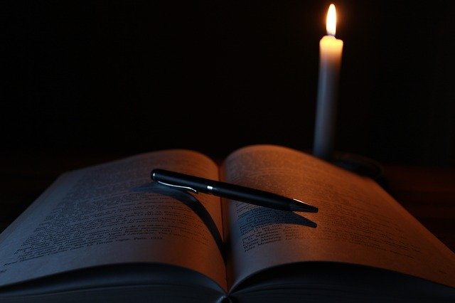 A book dimly lit by a candle suggesting secret knowledge